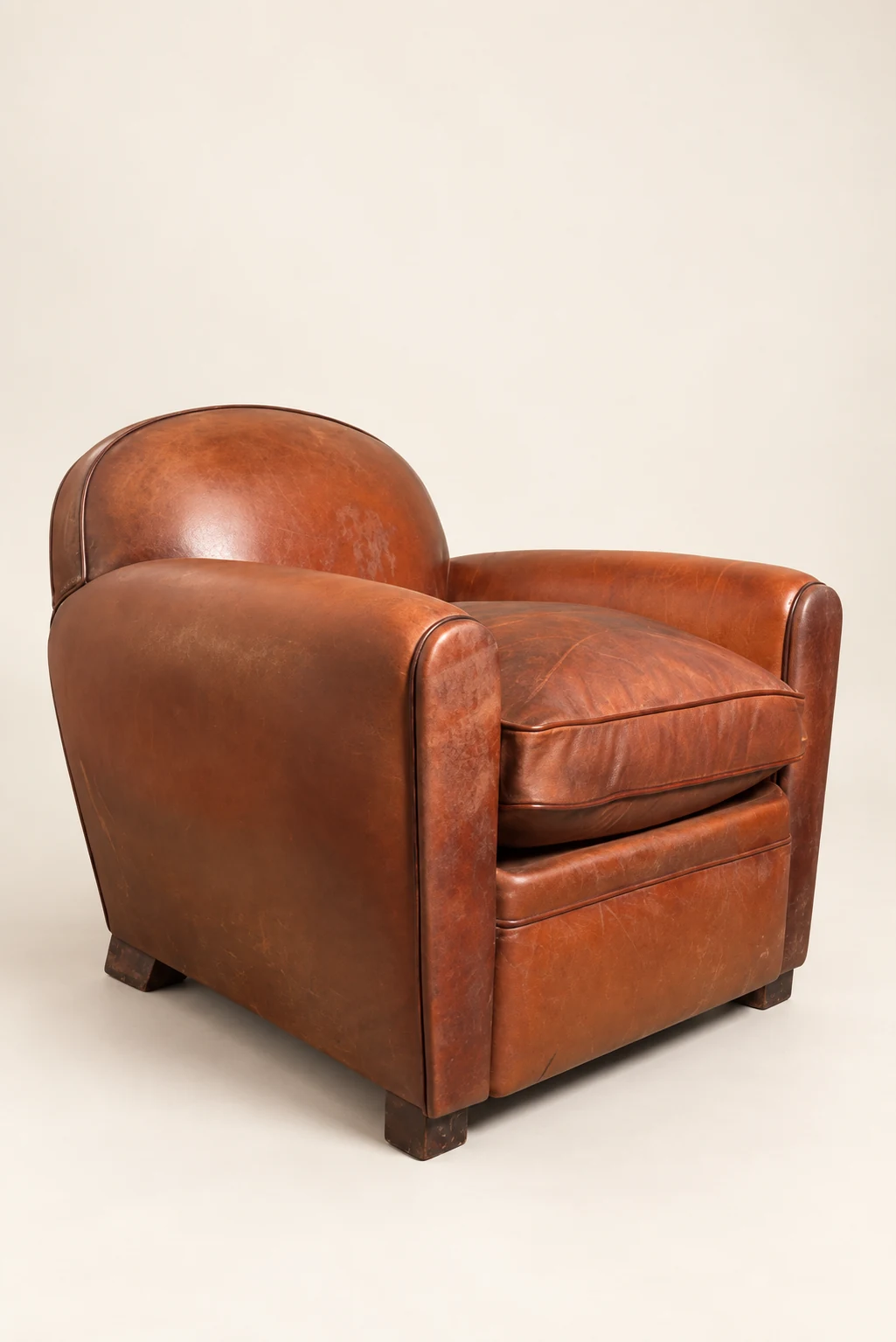 Brown barrel-back leather armchair, three-quarter studio view